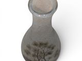 a glass vase with a tree on it on a white surface