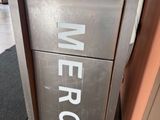une boîte métallique sur laquelle est apposée une étiquette portant l'inscription « merc »