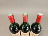 three bottles of red wine are lined up in a row