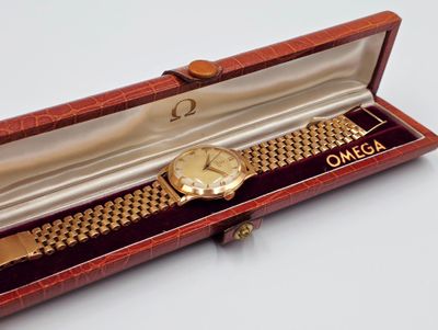 a gold watch in a red box on a white surface