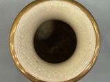 a white vase with a gold rim on a table