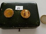 a small metal box with two gold buttons on it