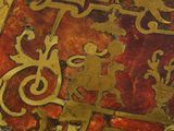 a close up of a gold and red book with designs on it