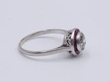 a close up of a silver ring with a red stone