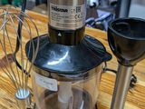 a blender sitting on top of a wooden table next to a whisk and a whisk