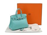 un sac à main bleu posé sur une table, à côté d'une boîte