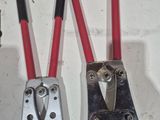 two red and black pliers on a white table with a sign