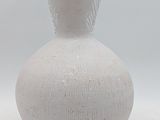 a white vase with a brown handle sitting on a table