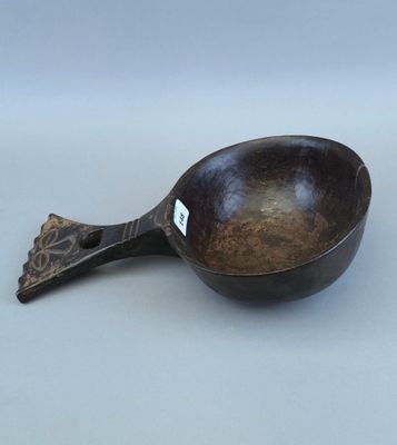 une vieille cuillère en bois avec un manche en métal posée sur une surface blanche