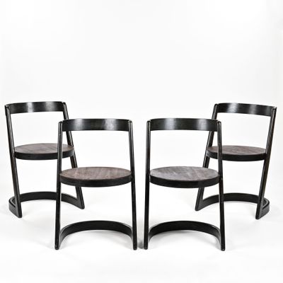 trois chaises en bois noires placées les unes à côté des autres sur une surface blanche