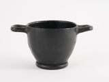 a black cup that is sitting on a white surface