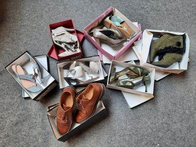 plusieurs paires de chaussures dans une boîte posée sur le sol