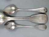 three silver spoons and two silver spoons on a table