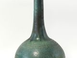 un vase vert posé sur une surface blanche