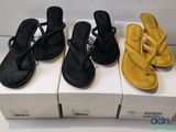 three pairs of black and yellow sandals sitting on top of boxes