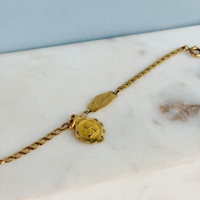 un gros plan d'un bracelet plaqué or orné d'une pièce de monnaie