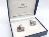 deux boutons de manchette en argent dans un coffret bleu sur fond blanc