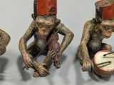 three figurines of monkeys playing musical instruments on a table