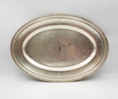 une assiette ancienne en argent sur fond blanc, avec un petit trou au milieu