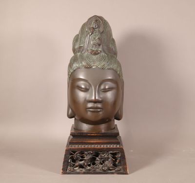 tête en bronze d'une statue de Bouddha posée sur un socle en bois