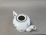 a small white tea pot with a blue star design on it