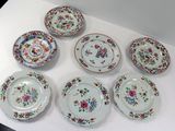 Plusieurs assiettes ornées de motifs floraux sont disposées sur une surface blanche