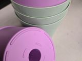 purple and green buckets sitting on top of a counter next to each other