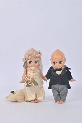 des figurines représentant la mariée et le marié, debout l'une à côté de l'autre sur une surface blanche