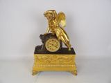 a gold clock with an angel on top of it