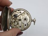 a person holding a silver pocket watch in their hand
