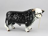 une figurine de vache en noir et blanc avec une corde dans la bouche