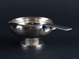 a silver bowl with a spoon in it on a black surface