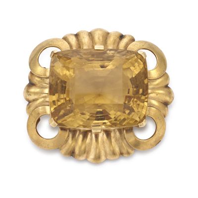 un gros plan d'une broche en pierre jaune sur fond blanc