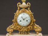a gold clock sitting on top of a marble table