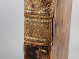 an old book sitting on top of a wooden table next to a white wall