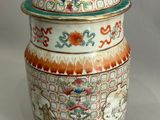 un grand vase avec un couvercle posé sur une table blanche