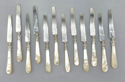 six couteaux argentés et six couteaux posés sur un support gris