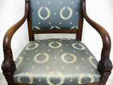 an old chair with a blue upholstered seat and a wooden frame