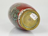 a red and green vase sitting on a white surface