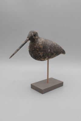 statue représentant un oiseau au long bec, posée sur un socle en bois