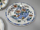 a plate with a rooster and flowers on it on a table