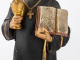 figurine of a monk holding a book and a golden cup