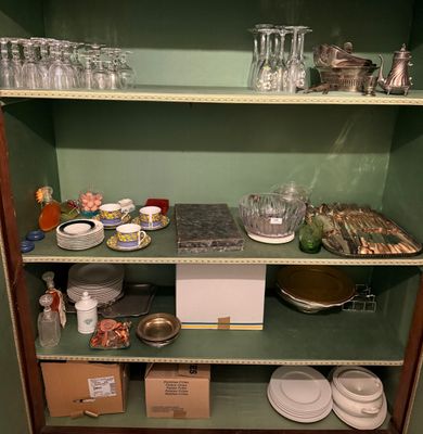 a green cabinet with a lot of dishes and glasses on it