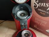 une cafetière rouge posée sur une table à côté d'une boîte