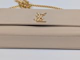 a close up of a beige purse on a white surface