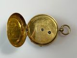 an antique gold pocket watch with a blue stone in it