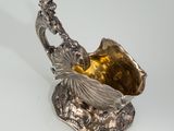 a silver plate with a bird on it on a white surface