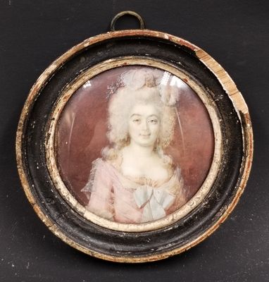 une vieille photo d'une femme en robe rose, dans un cadre rond