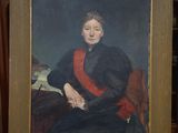 painting of a woman in a black dress sitting on a red chair