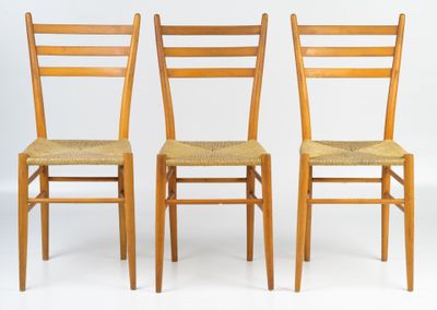 three wooden chairs with woven seats against a white background